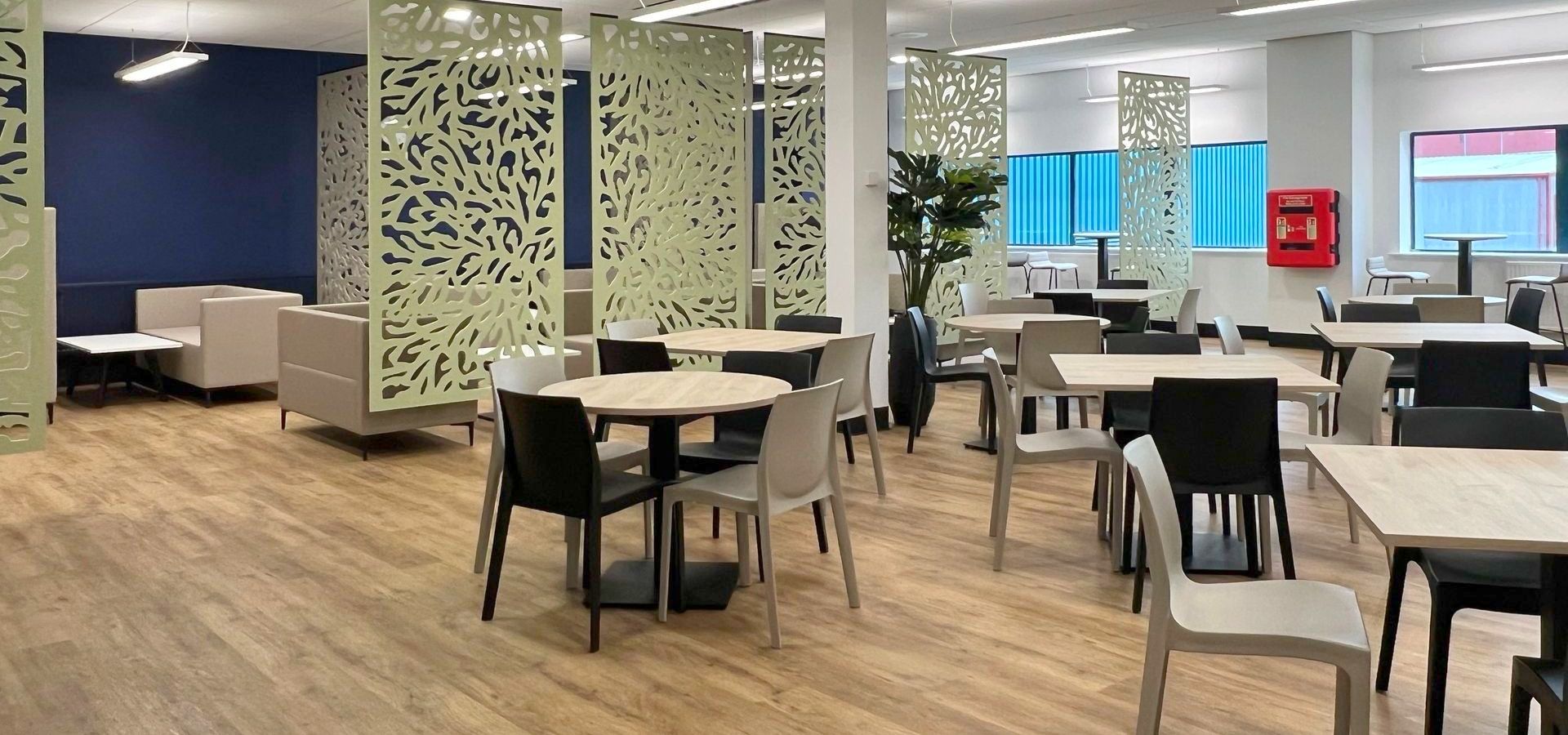 Autex acoustic ceiling-hung screens in a modern canteen space with bistro tables, café chairs, soft seating and planters,