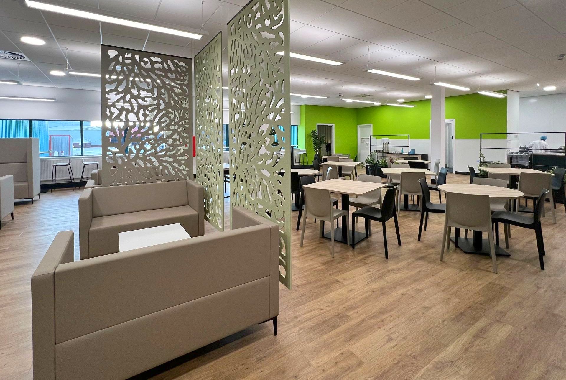 Autex acoustic ceiling-hung screens in a modern canteen space with bistro tables, café chairs, soft seating and planters,