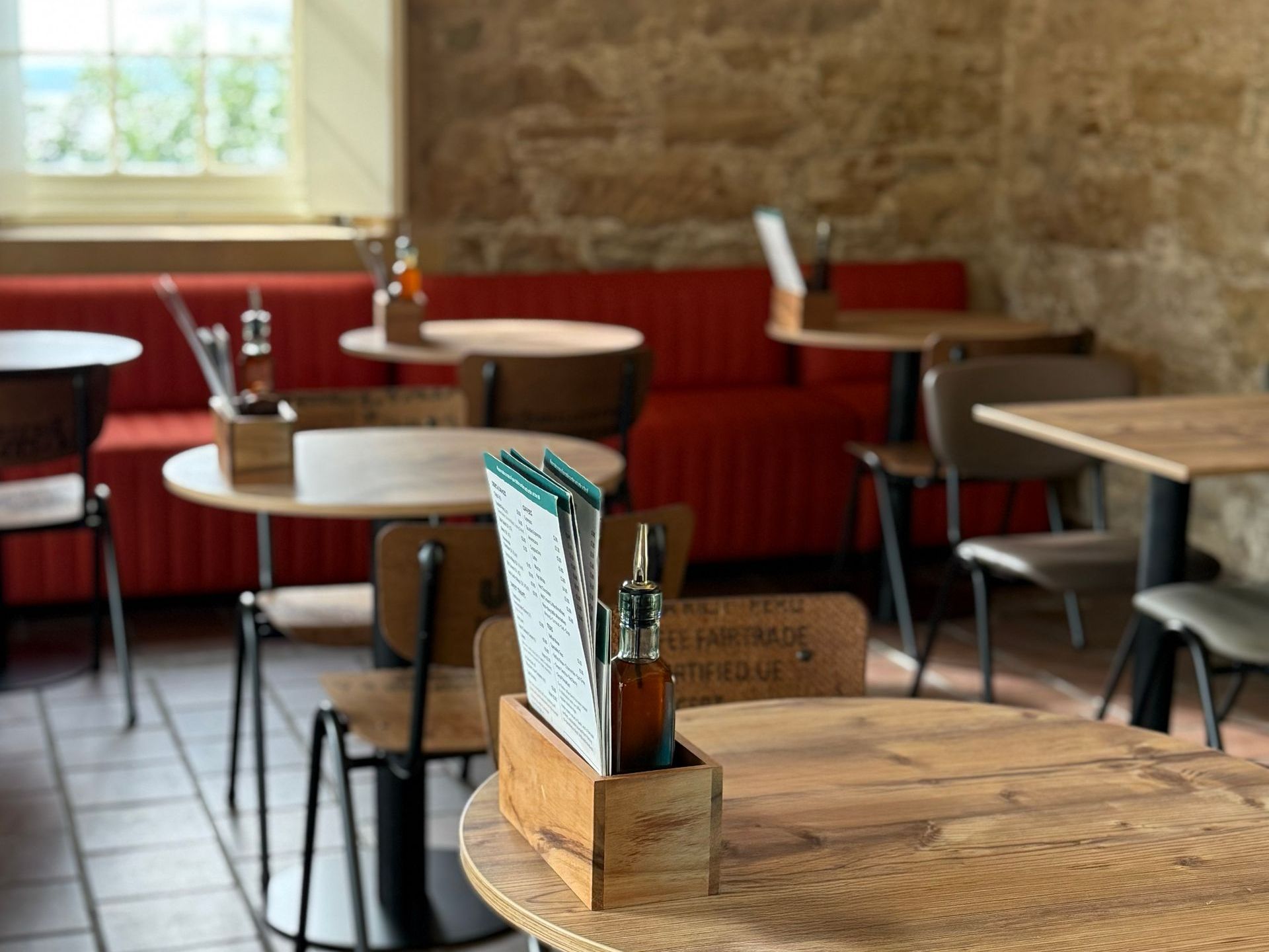 Culzean castle restaurant interior with wooden tables and chairs, red booth seating, and stone walls.