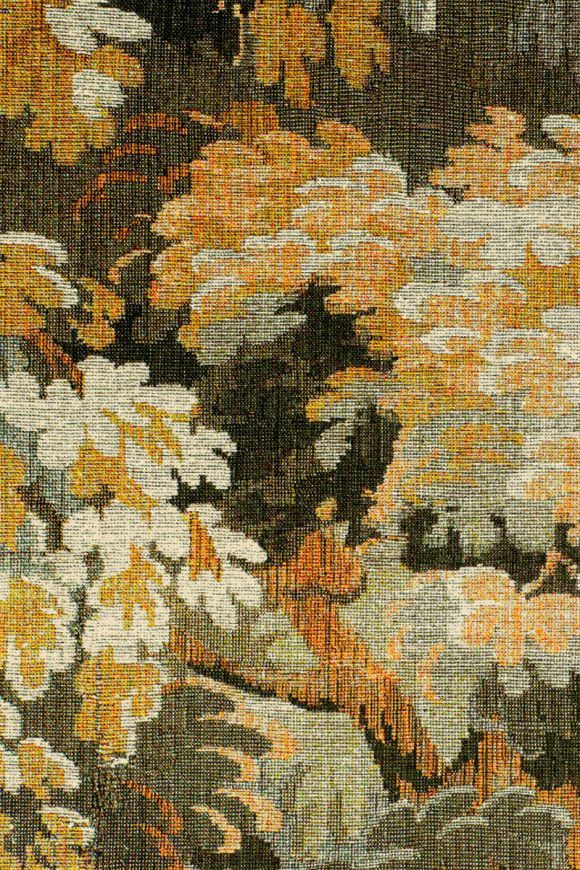 Tapestry with stylized foliage in autumnal colors of gold, white, and brown on a dark background.