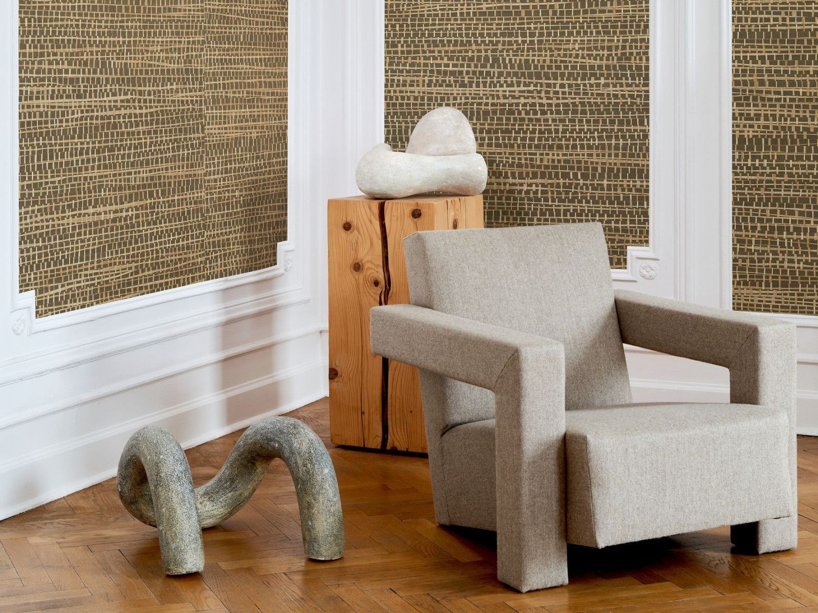 Neutral-toned room with abstract sculptures, a textured chair, and sustainable wallpaper.