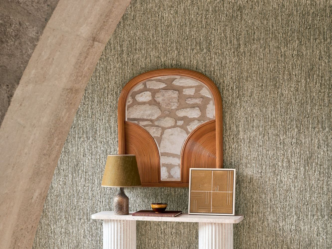Rattan chair with stone backing over a white mantel with decor against textured green wall.