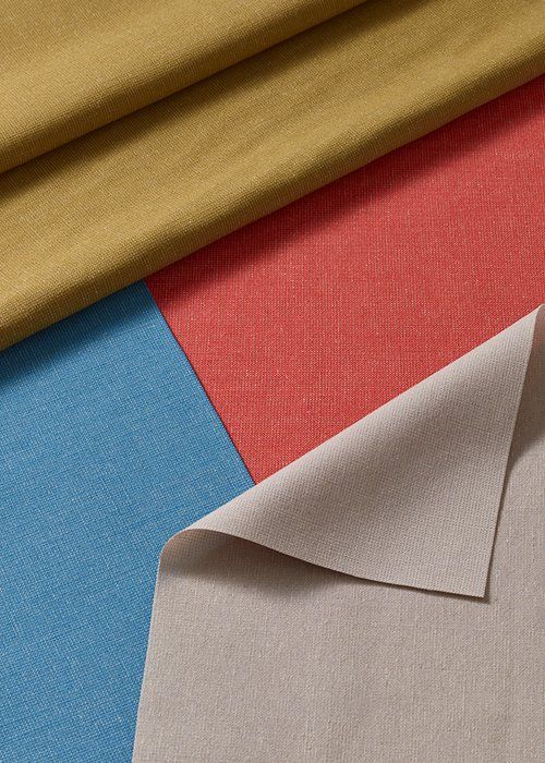 Close-up of fabric swatches in blue, red, yellow-tan, and beige, with the beige swatch flipped.