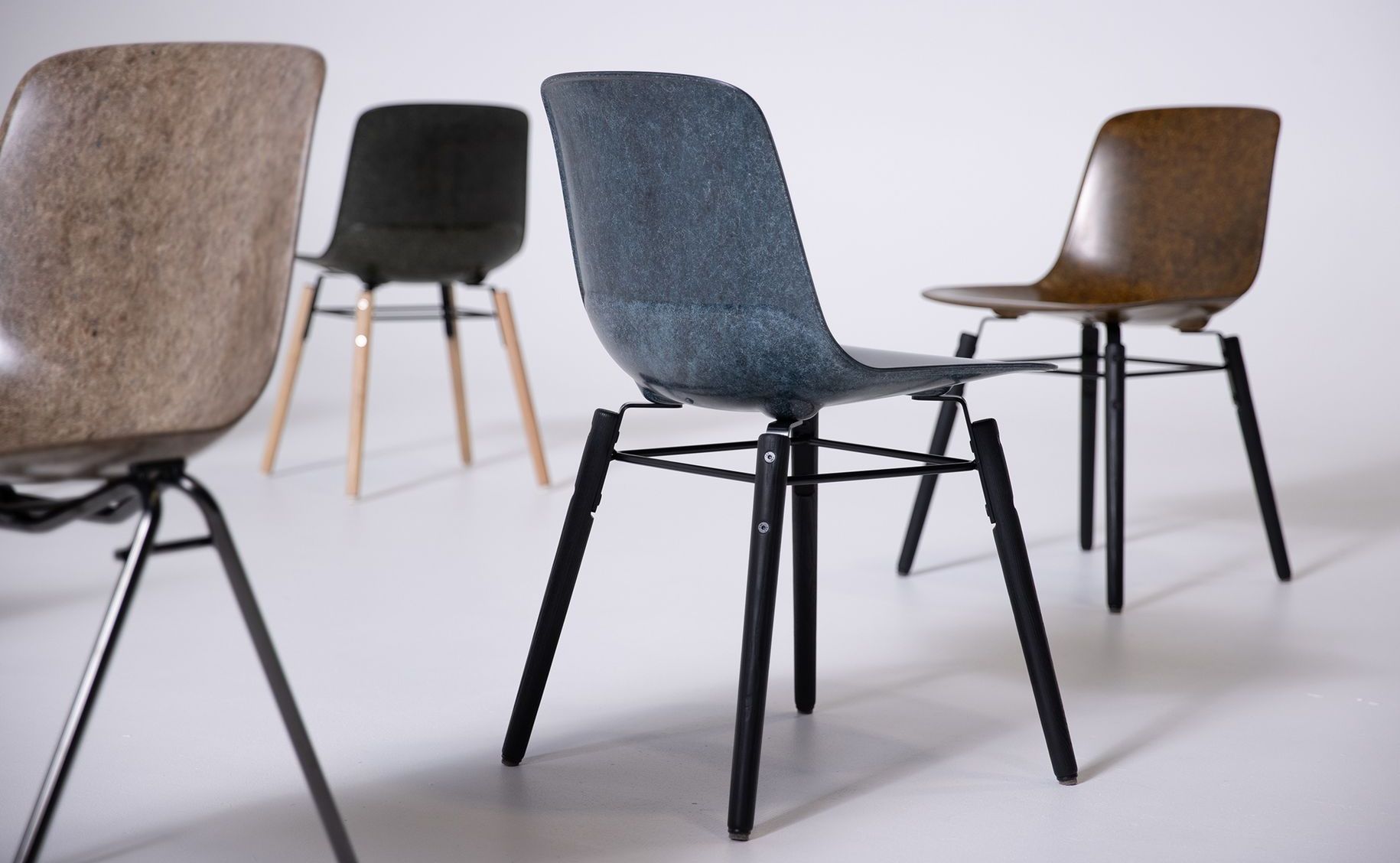 Hembury chairs arranged artistically in a white studio space in various colours, including cobalt and tan.
