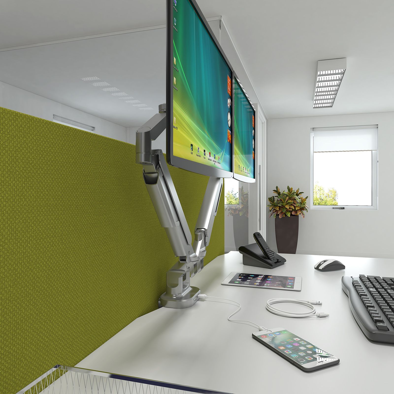 Work desk with two monitors mounted on an articulated arm; green divider; white desk, phone, phone, mouse, keyboard.