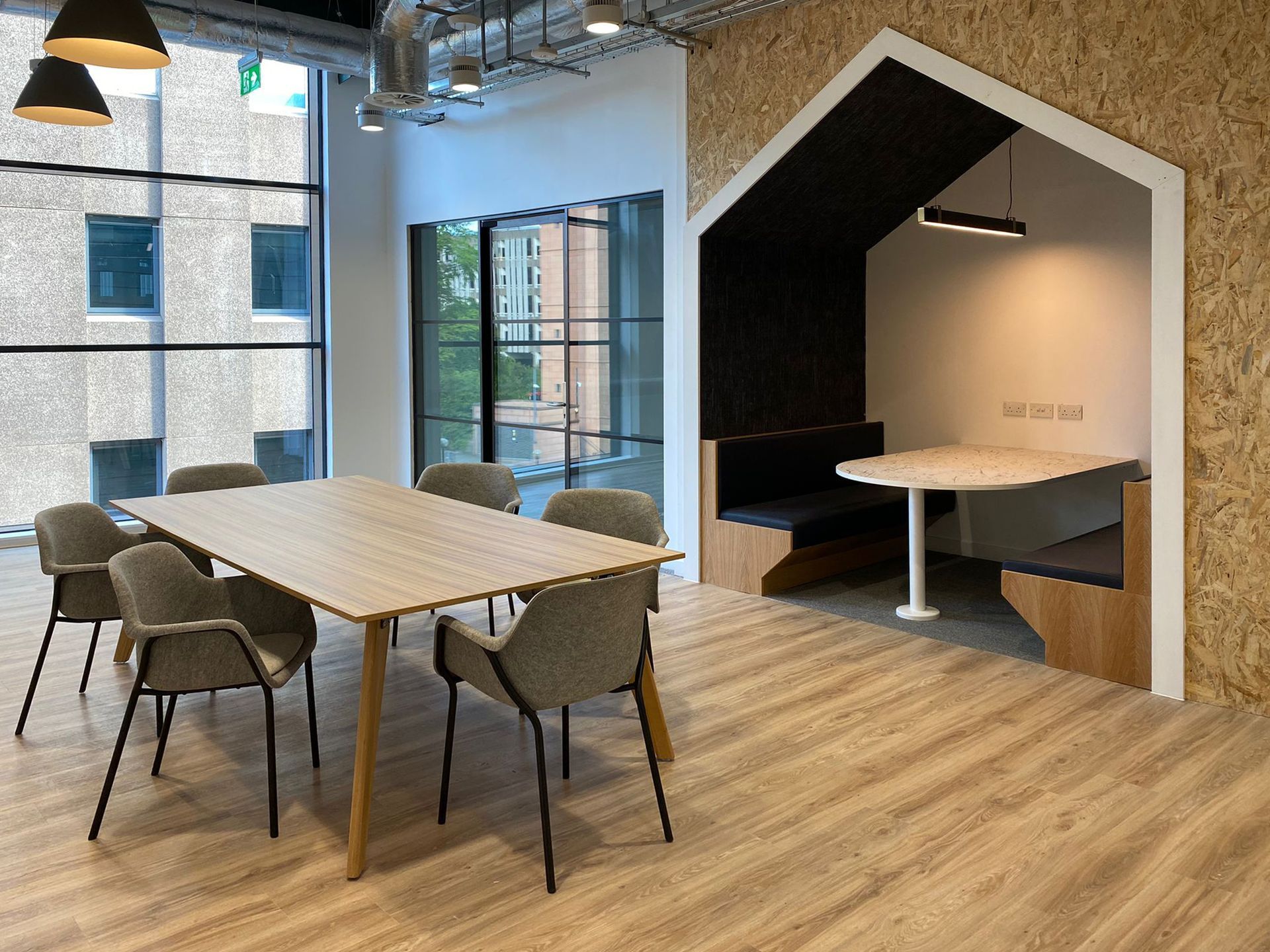 This area of the space features a shorter conference table with wing chair seating. In the background is an integrated booth with built-in seating. The interior of the booth is black and white with a built-in table and sockets.