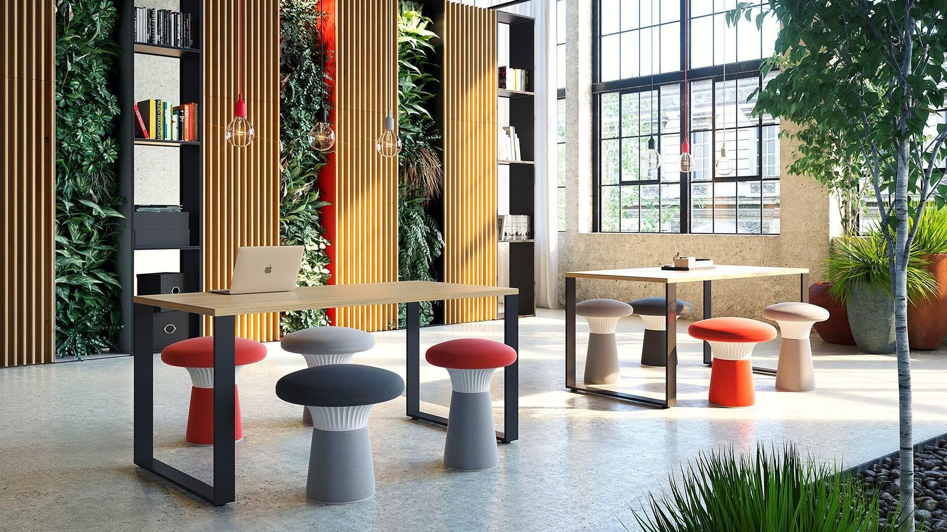 there are two desks in the middle of a large, naturally lit room. at ecah table are mushroom shaped stools. on thetables are a laptop and stationary on the back walls are wooden panels and thriving greenery, shelves with storage and books. 