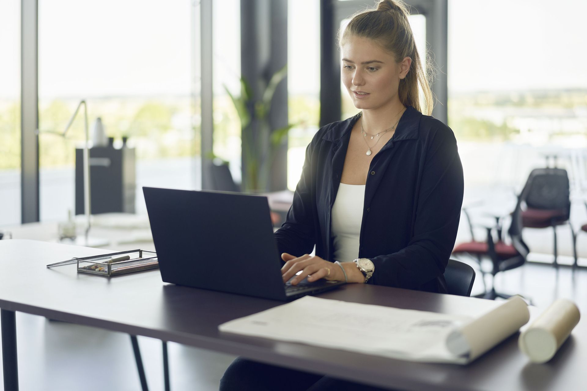 woman sitting at a desk in an ergonomic office chair working on her laptop.
