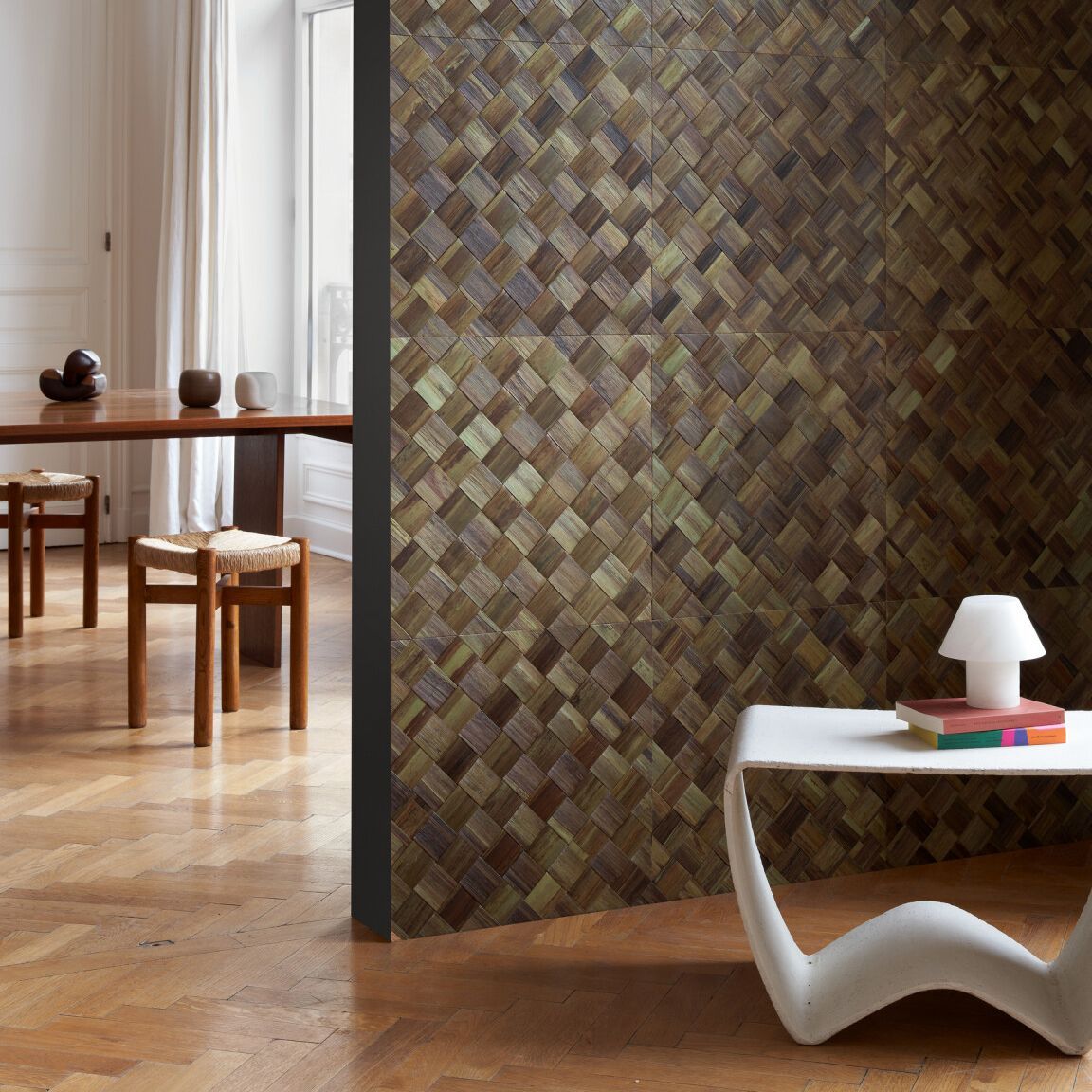 Dining room interior with a wood-patterned wall, table, chairs, and a modern white side table with a lamp.
