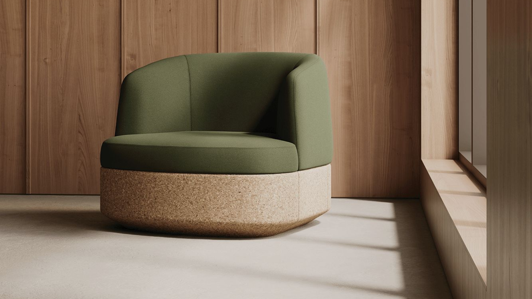 Green upholstered armchair with a cork base against a wood-paneled wall and a window.