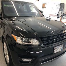 A front-facing view of a polished black Range Rover parked in a garage with overhead lighting.