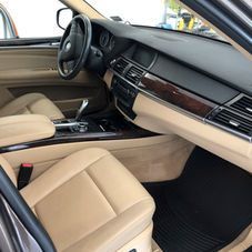The interior of a vehicle featuring tan leather seats, a black dashboard, wood grain trim, and a steering wheel.
