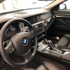 Interior view of a black BMW cockpit featuring a leather-wrapped steering wheel, digital dashboard, and center console.