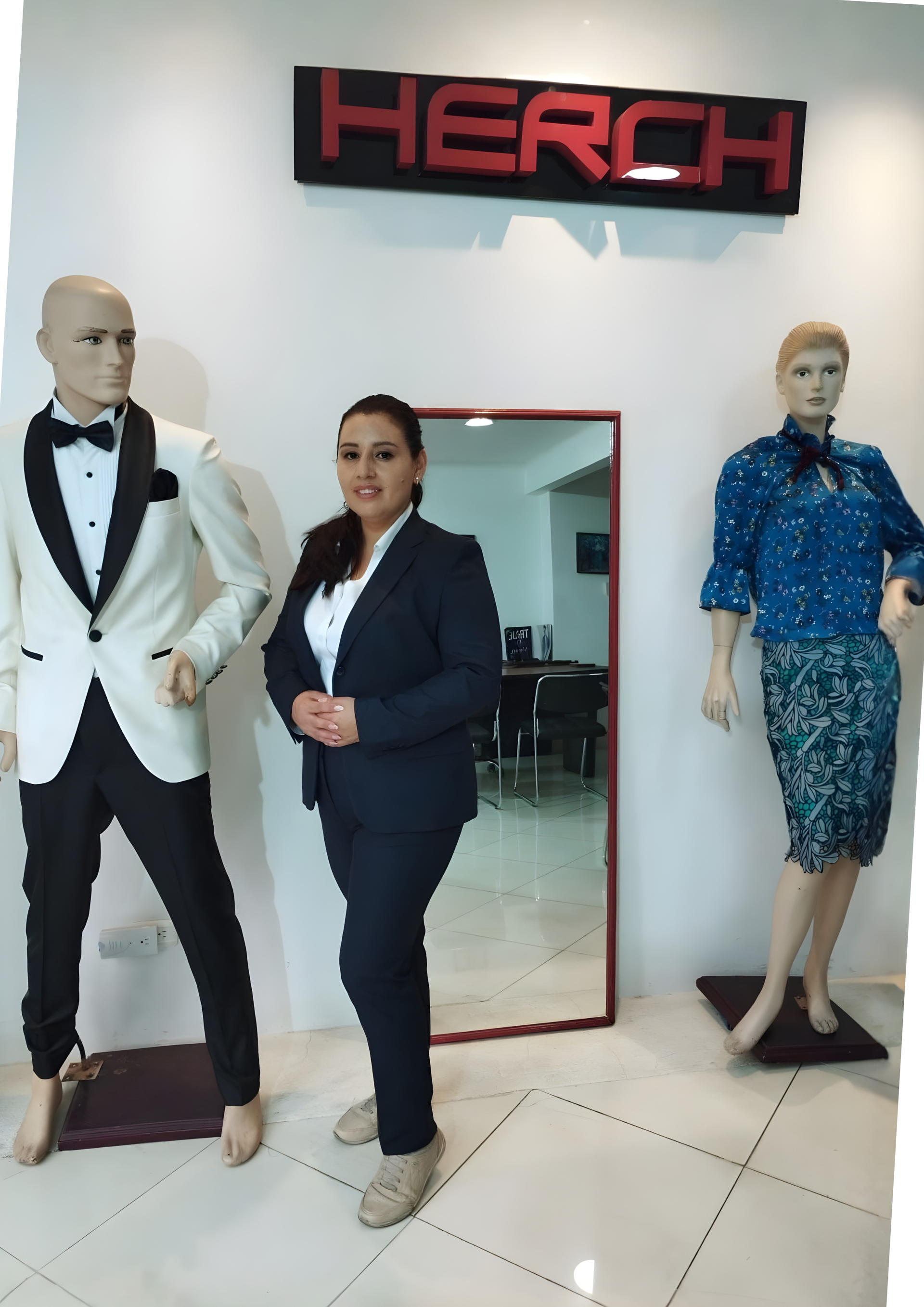Mujer con traje se encuentra entre maniquíes en las oficinas de HERCH UNIFORMES