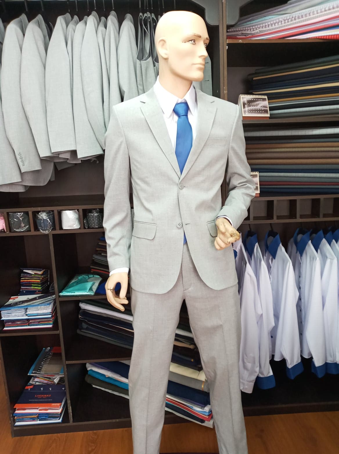 Maniquí de hombre vestido con terno gris claro, camisa blanca y corbata azul