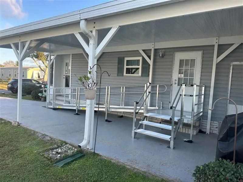 Covered porch with ramps and steps leading to a gray house entrance