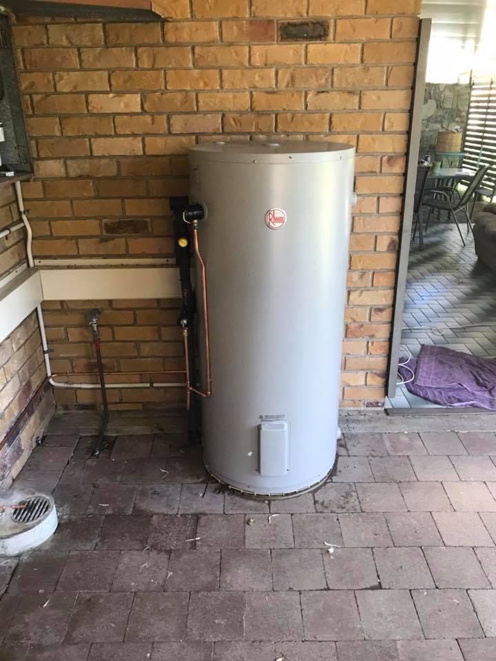 A Tall Cylindrical Water Heater and An AC Unit Outside a Building — McGill Plumbing & Gas in Beaconsfield, QLD