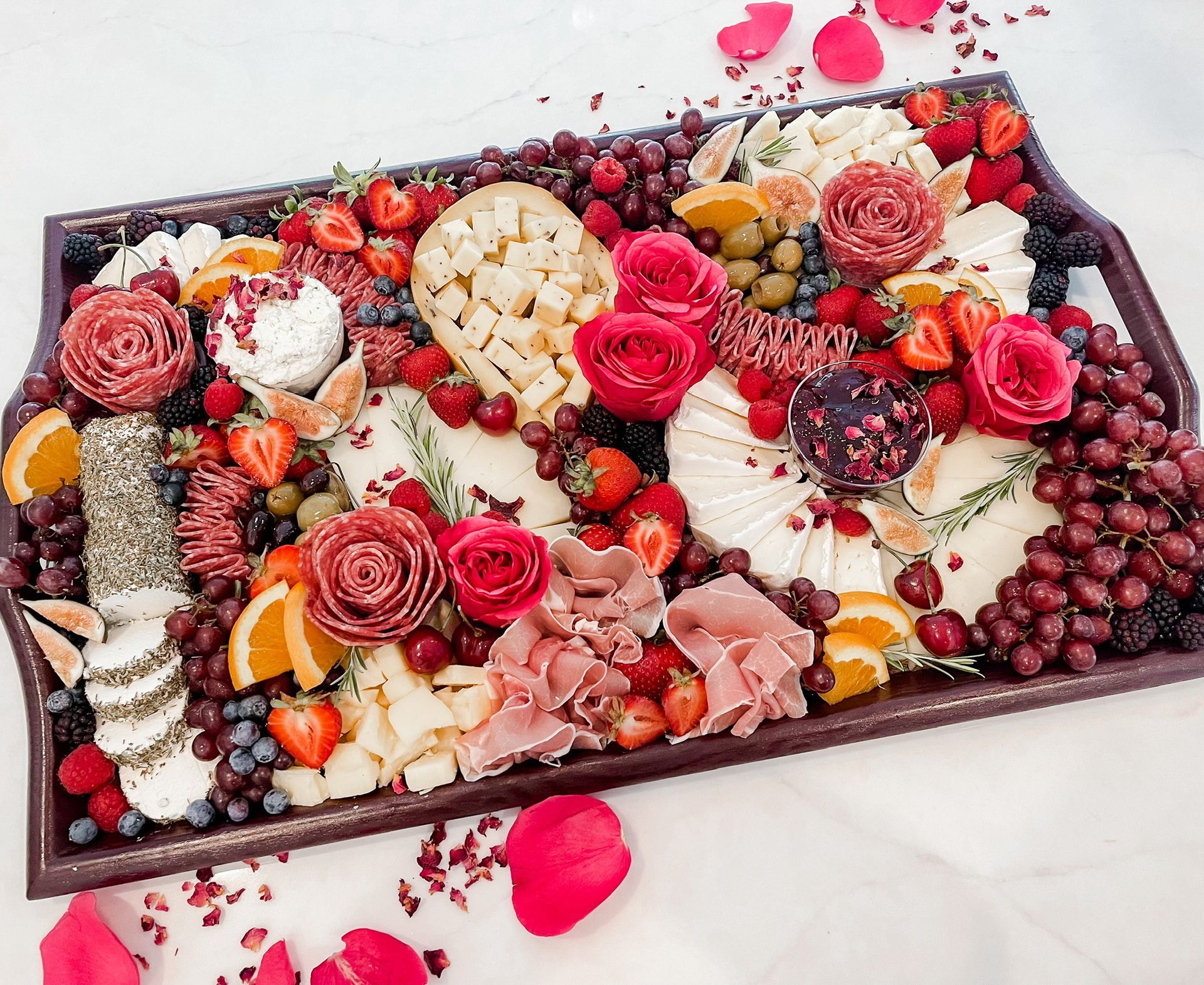 A large tray filled with fruits and meats on a table.