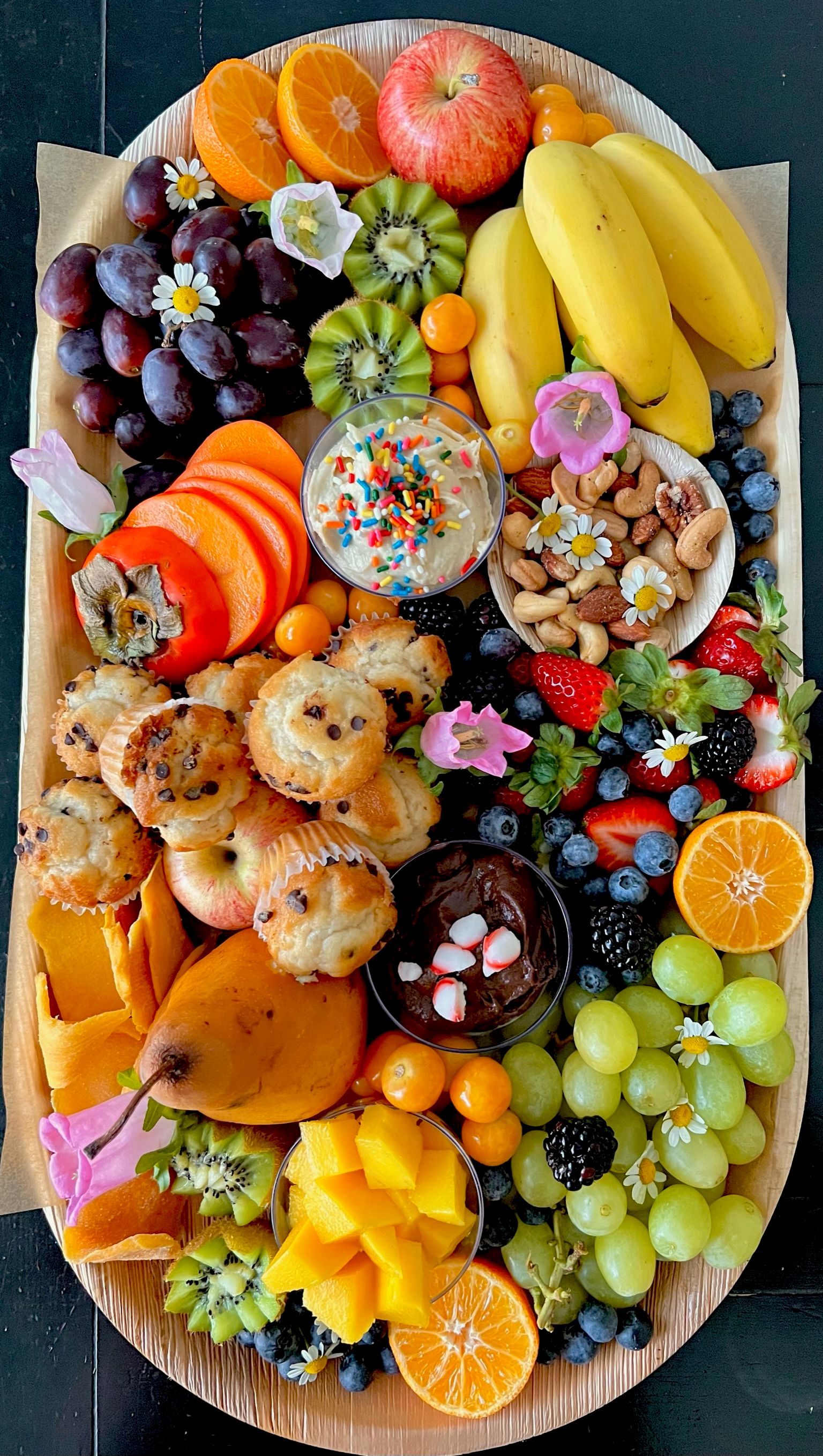 A wooden tray filled with lots of fruit and nuts.
