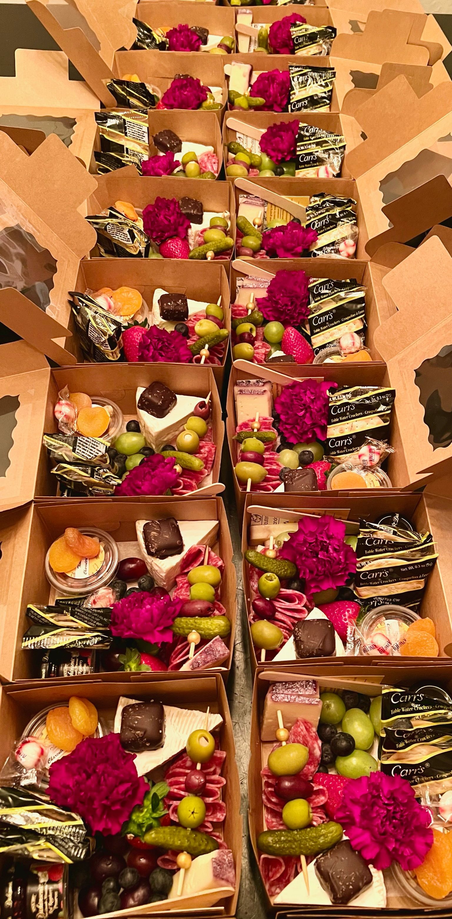 A row of cardboard boxes filled with food and flowers.