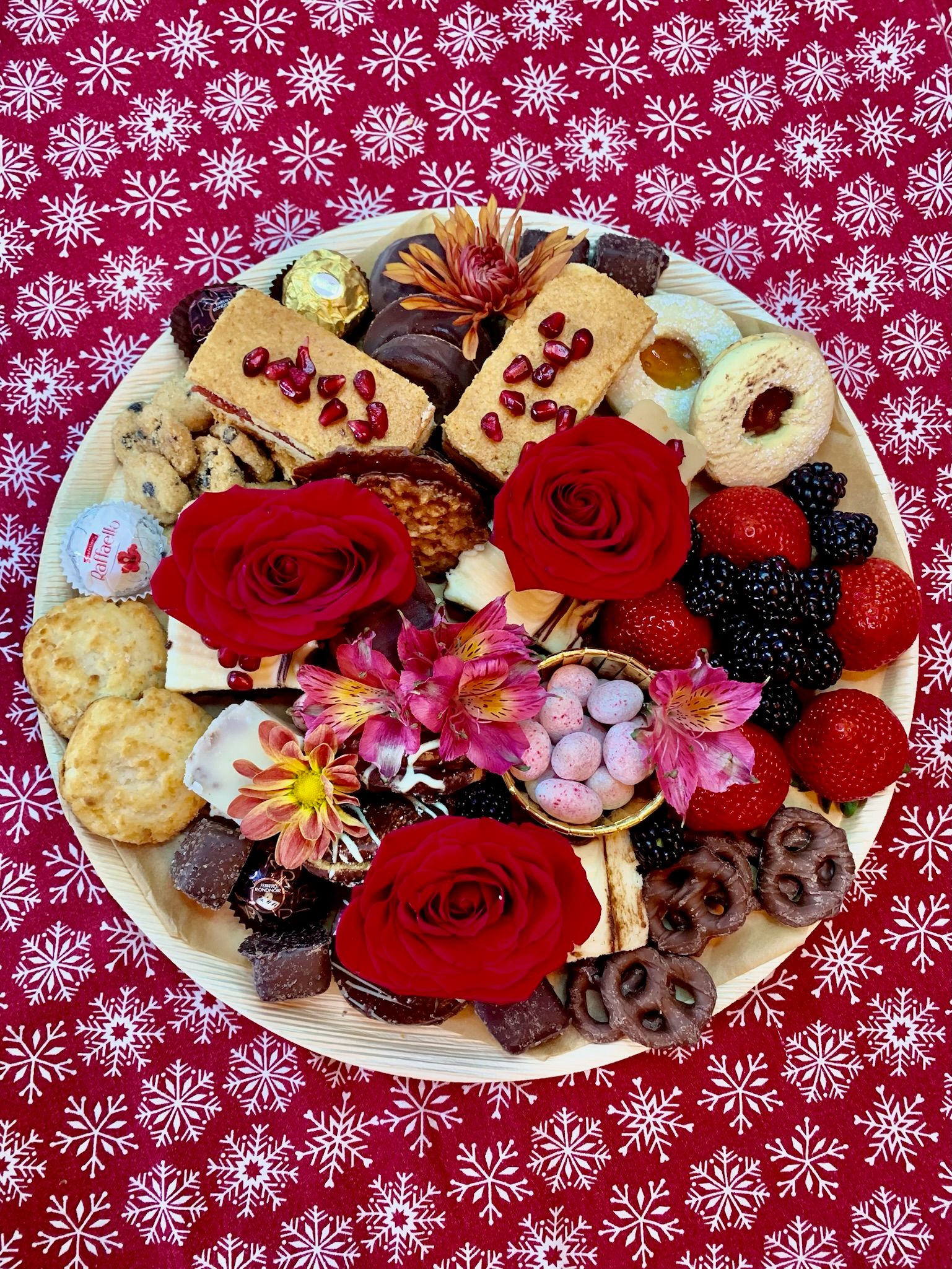 A plate of cookies and berries on a red table cloth