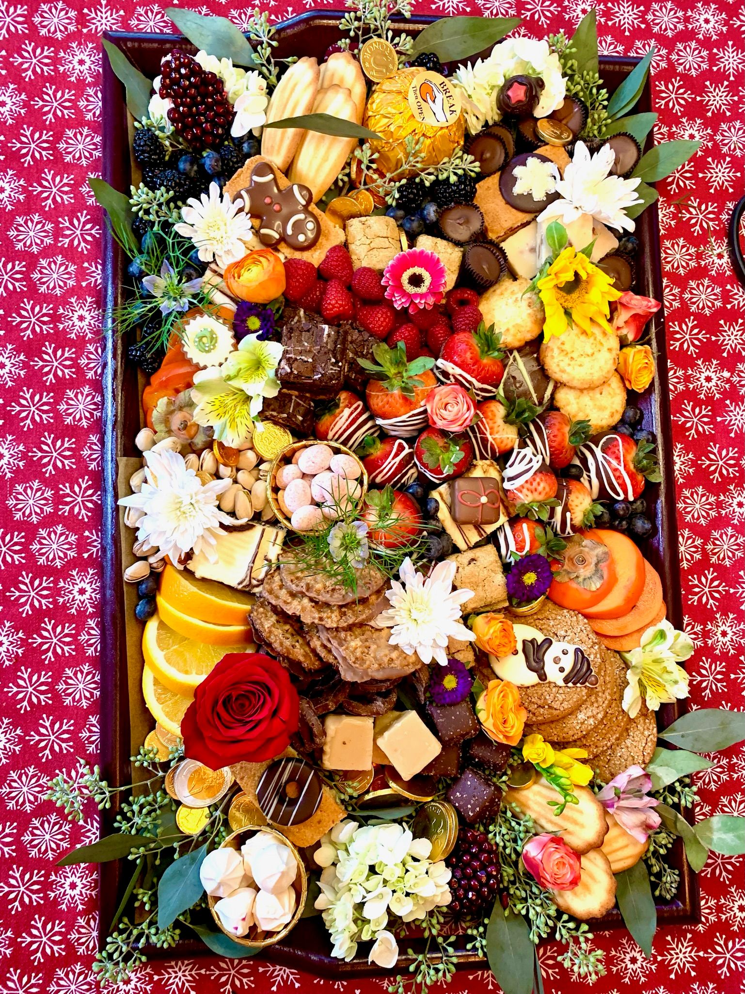 A large platter filled with lots of food and flowers on a table.