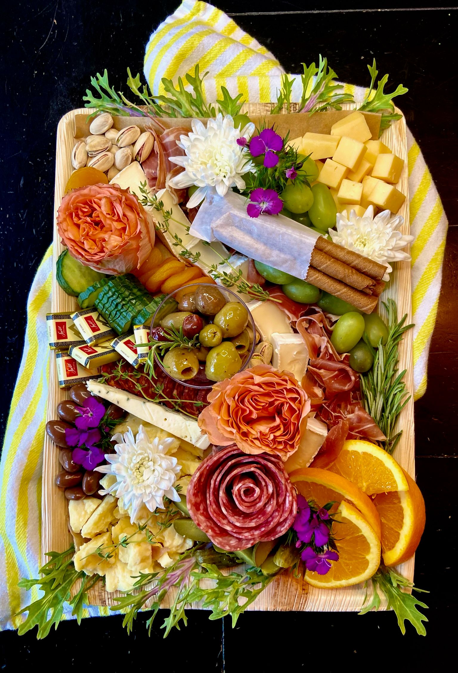A cutting board filled with lots of different types of food and flowers.