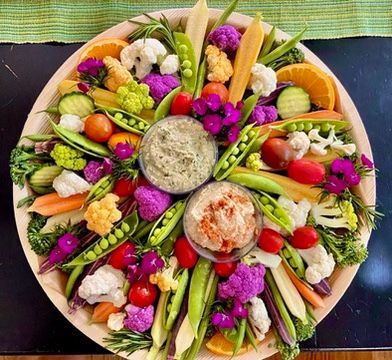 A plate of vegetables and flowers on a table.