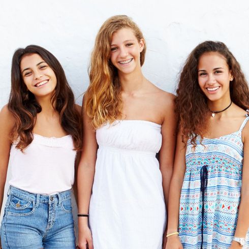 Three young women are posing for a picture and smiling for the camera