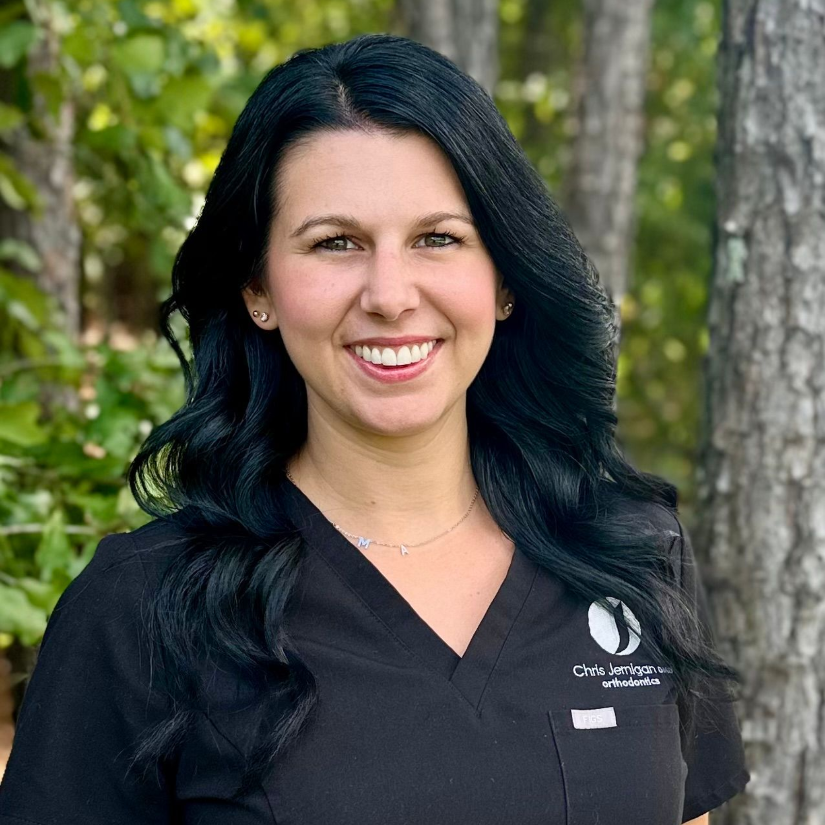 A woman in a black scrub top is smiling for the camera.