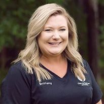 A woman in a black scrub top is smiling for the camera.