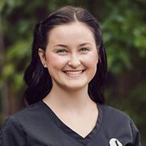 A woman in a black scrub top is smiling for the camera.