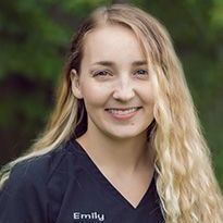 A woman in a black scrub top is smiling for the camera.