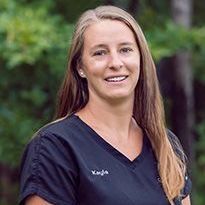 A woman in a black scrub top is smiling for the camera.