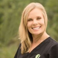 A woman in a black scrub top is smiling for the camera.