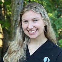 A woman in a black scrub top is smiling for the camera.