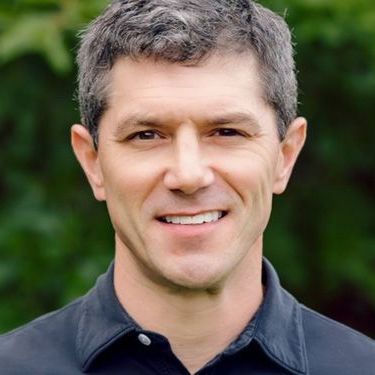 A man in a black shirt is smiling for the camera.