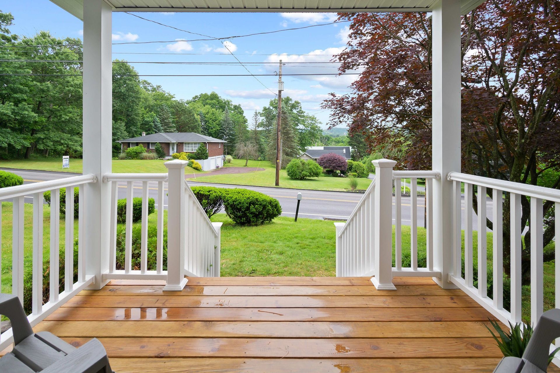 a porch with two chairs and a view of a house