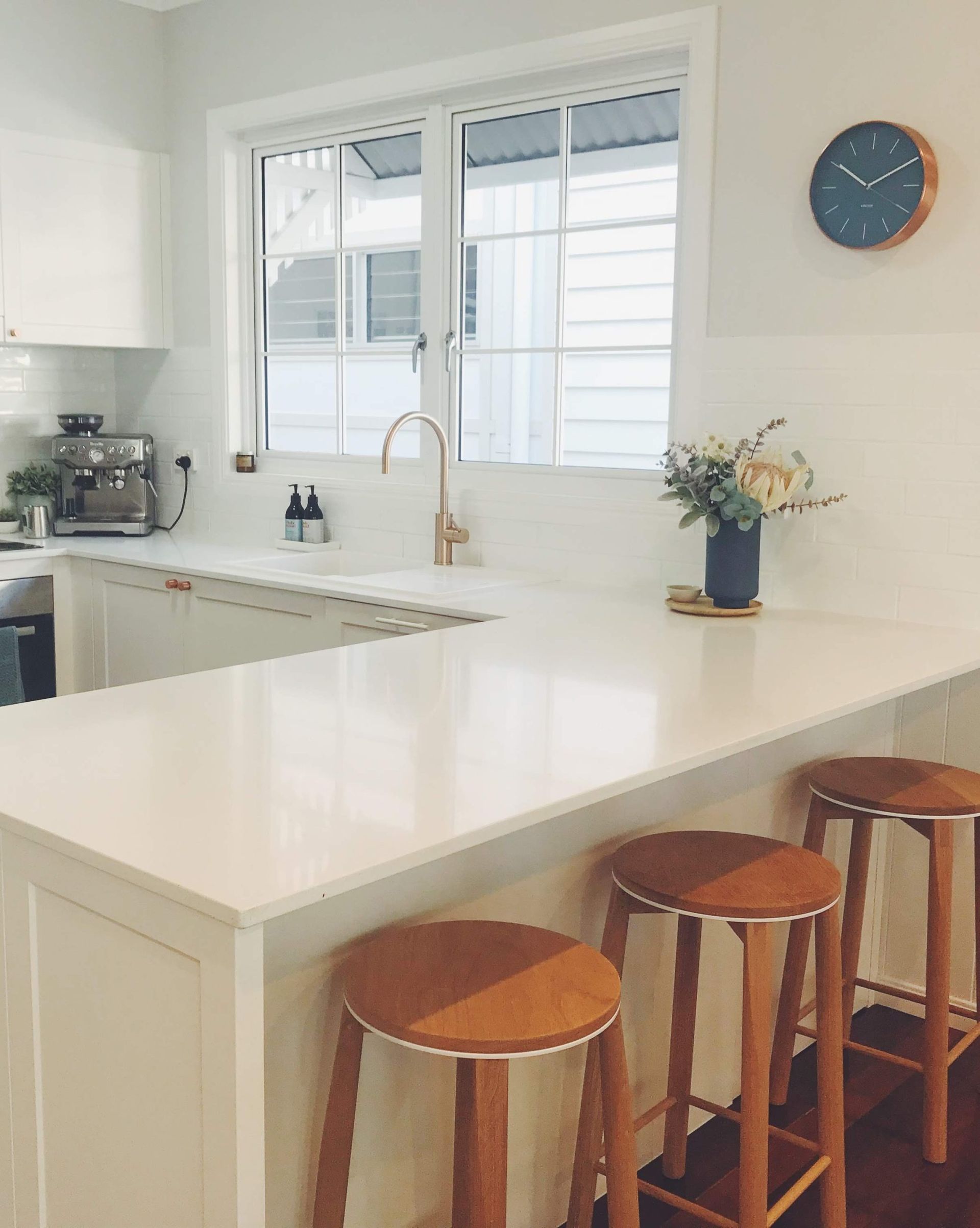 a kitchen with stools and a clock on the wall