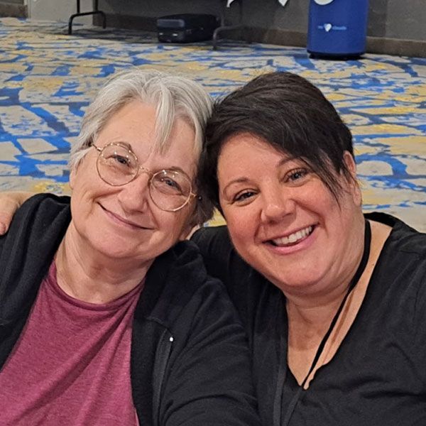 Two women are posing for a picture and smiling for the camera