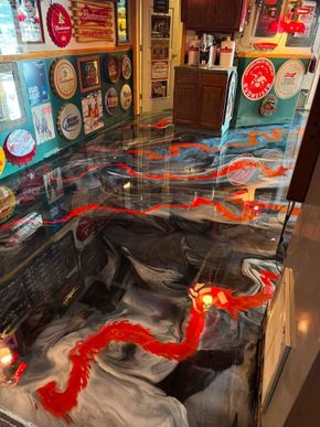 Colorful indoor art installation with a glossy black floor and red, blue, and silver swirling patterns