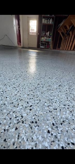 Low-angle view of a speckled terrazzo floor in a dim hallway with a doorway in the background