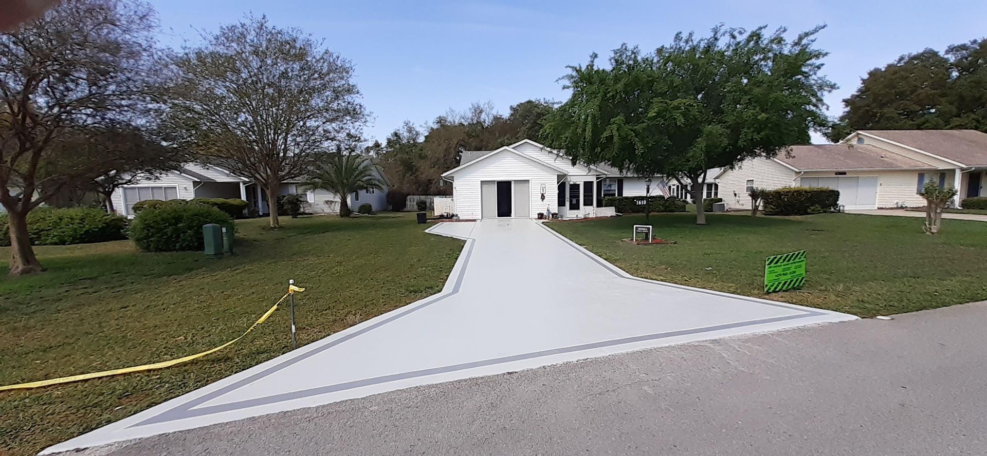 A driveway leading to a white house in a residential neighborhood.