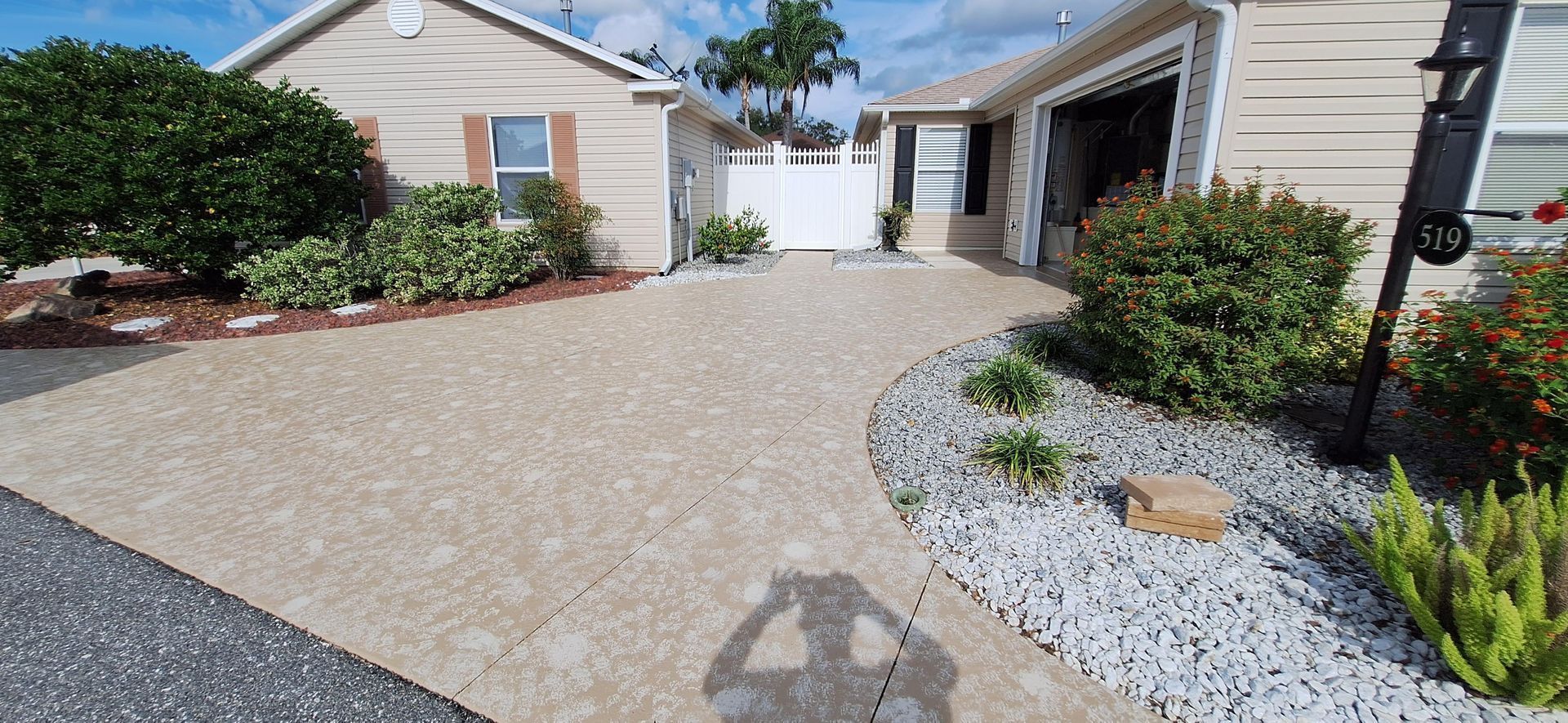 A house with a driveway and a shadow of a person on the ground.