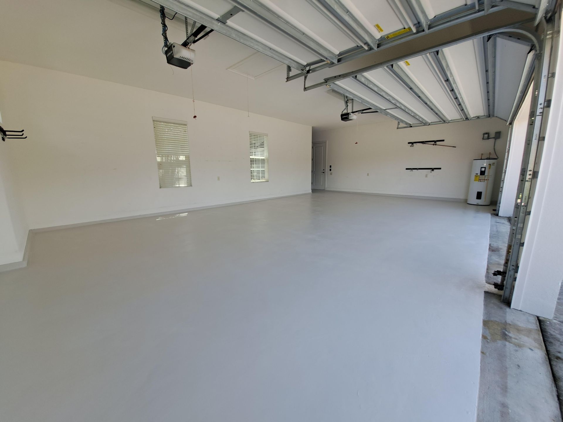 An empty garage with a garage door open and a white floor.