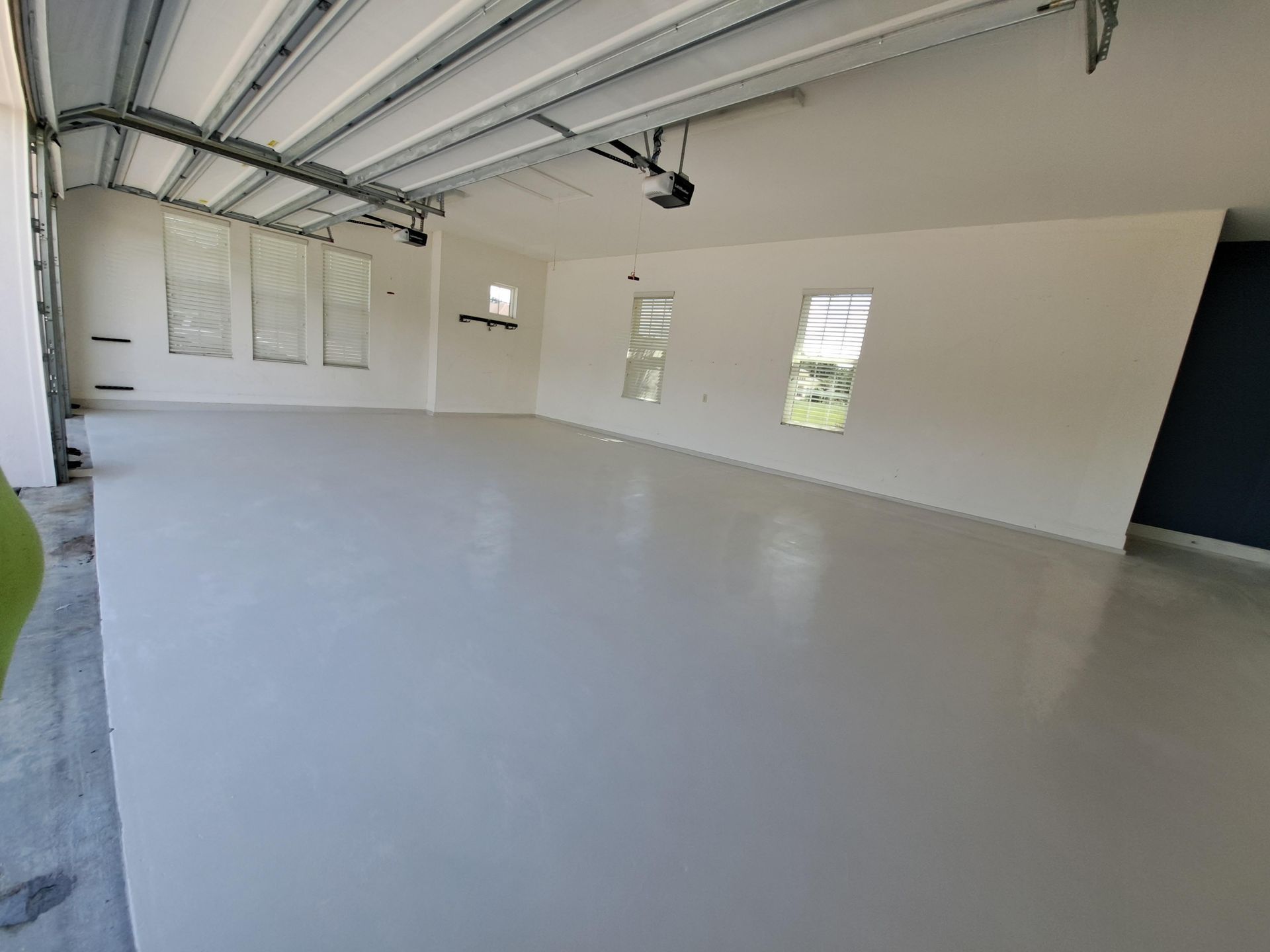 A large empty garage with a gray floor and white walls.