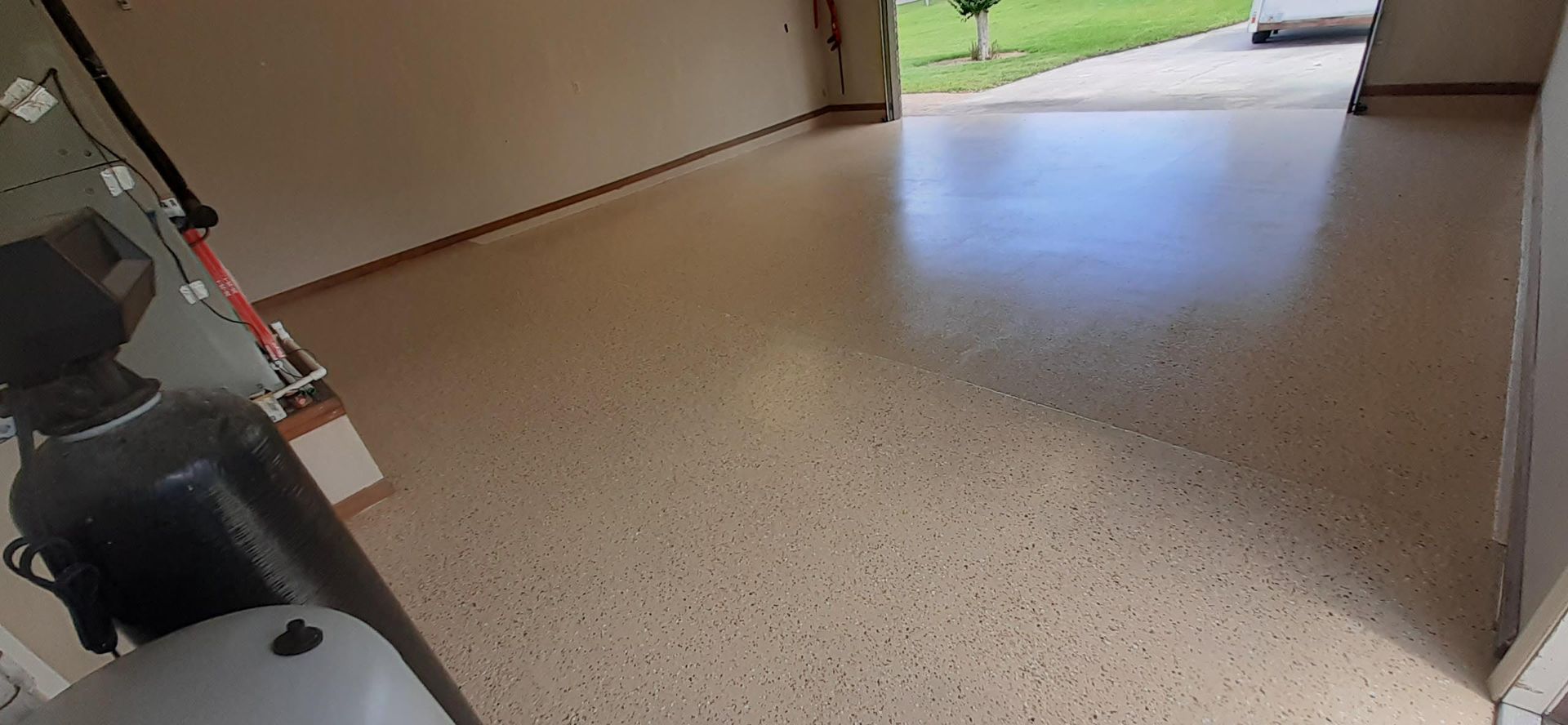 A garage with a concrete floor and a door open.