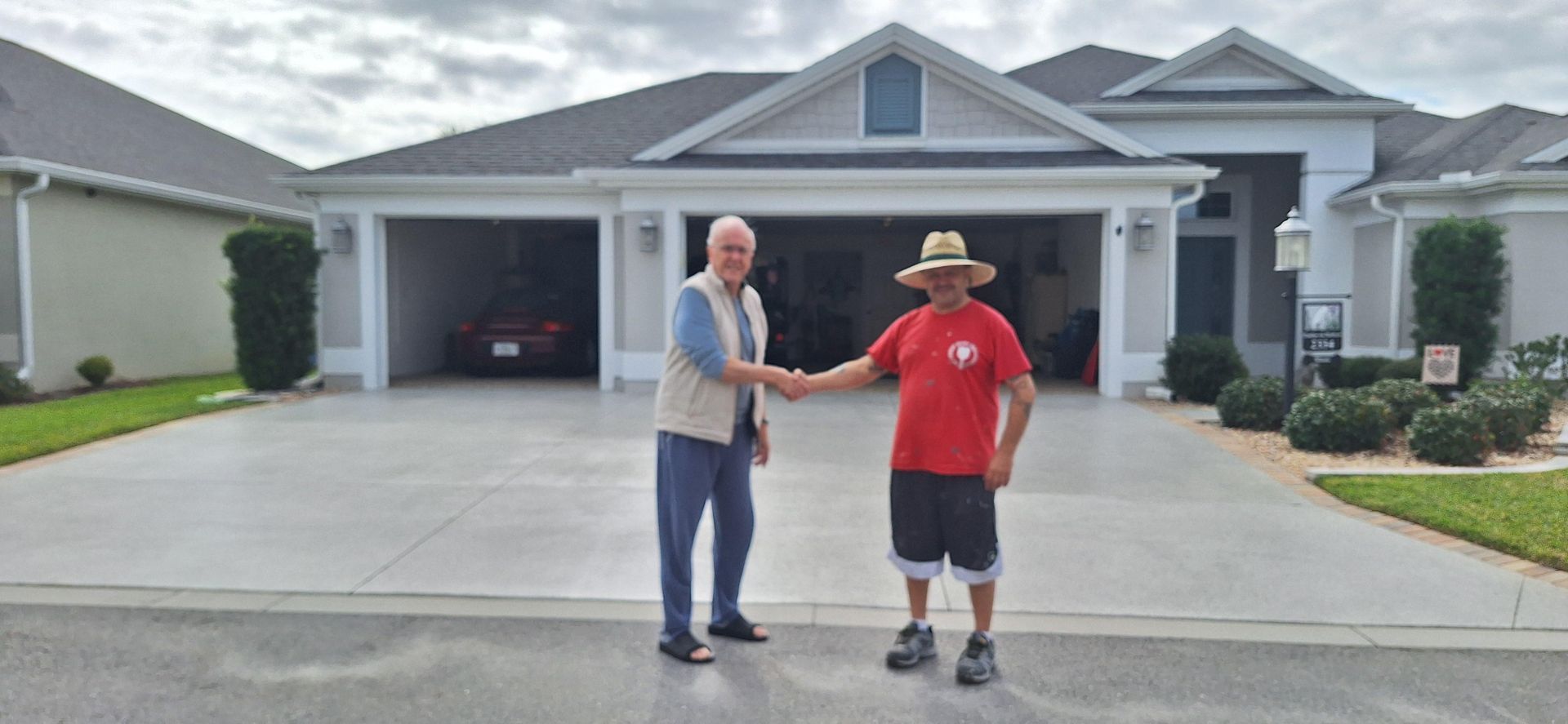 Two men are shaking hands in front of a house.