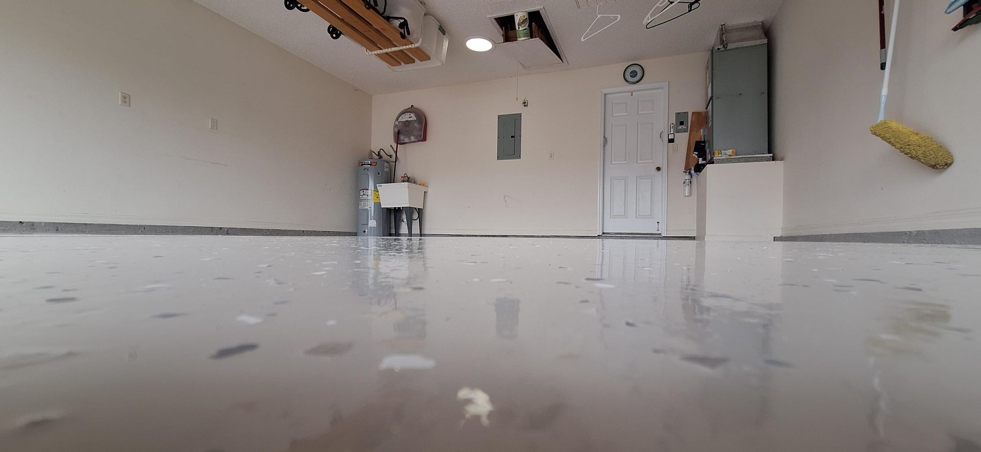 A garage with a sink and a mop on the floor.