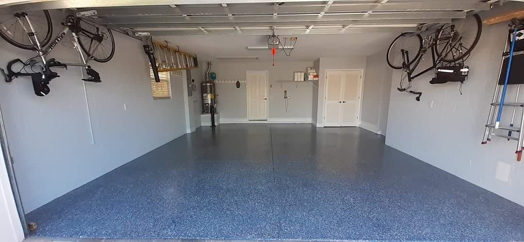 A large empty garage with bikes hanging from the ceiling.